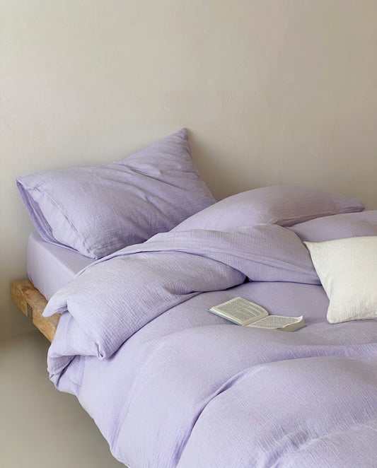 Lilac muslin cotton double gauze duvet cover set on a low wooden platform bed with a white pillow