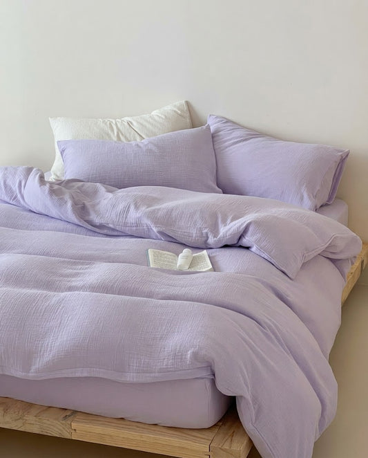 Lilac muslin cotton double gauze duvet cover and pillowcases styled on a wooden platform bed