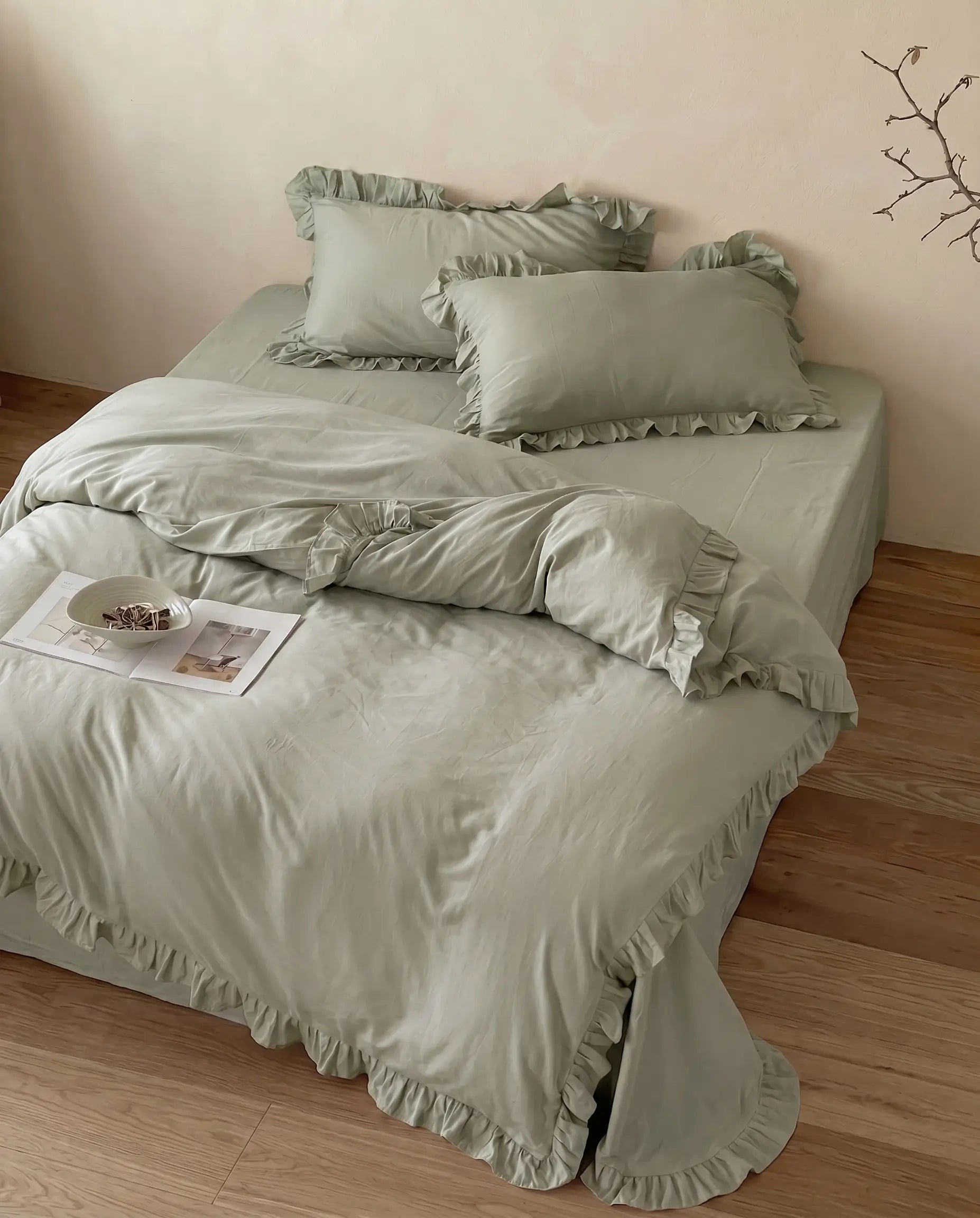 Luxury eucalyptus sage duvet cover set with matching ruffle pillow shams styled on a minimalist bed by DORMÉ Studio