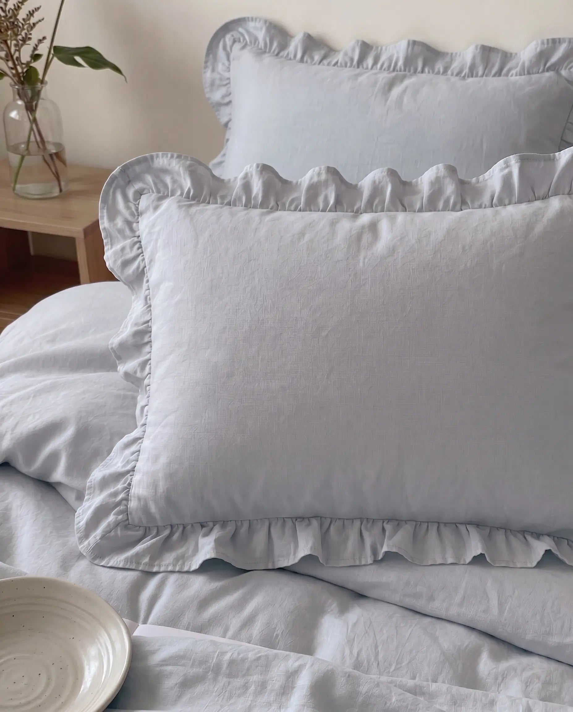 Luxury mist blue ruffle pillow shams styled on soft cotton bedding with delicate feminine detailing