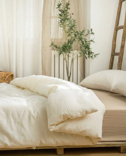 Luxury organic soybean fiber duvet insert with soft cotton shell on minimalist wooden bed frame, breathable hypoallergenic duvet insert by DORMÉ Studio.