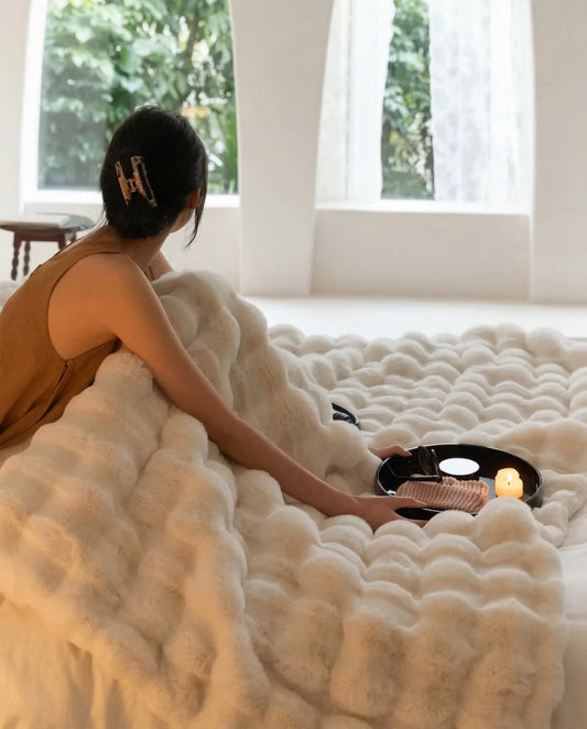 DORMÉ Studio Marshmallow Ultra Plush Blanket styled across bed with candle tray and magazine for luxury bedroom aesthetic. White