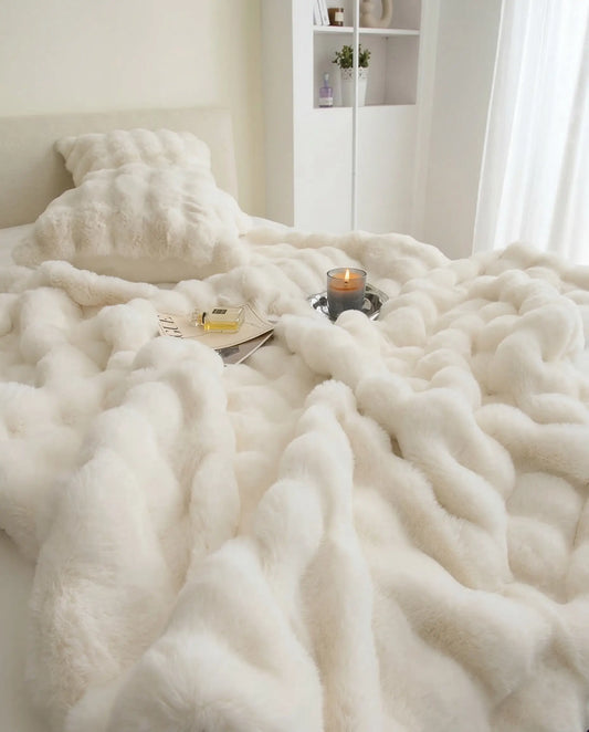 DORMÉ Studio Marshmallow Ultra Plush Blanket covering bed while woman relaxes beside tray with candle and accessories. White