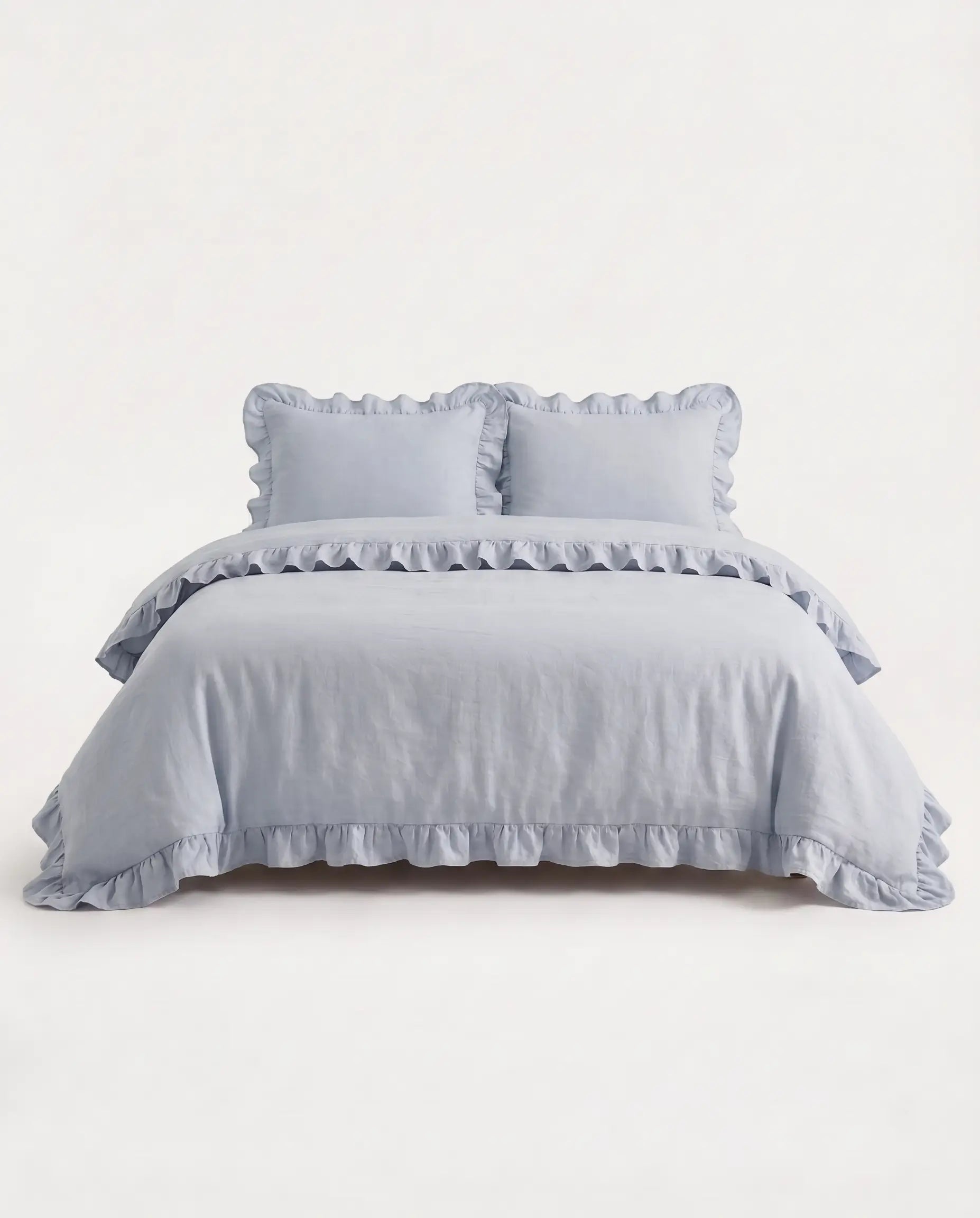 Front-facing studio image of the mist blue ruffle duvet cover set with matching pillowcases and elegant trim