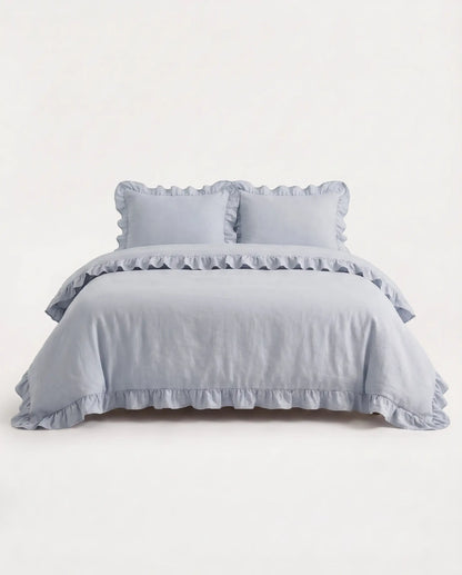 Front-facing studio image of the mist blue ruffle duvet cover set with matching pillowcases and elegant trim