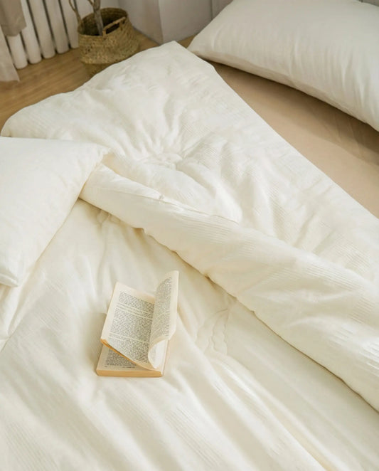 Organic soybean fiber duvet insert styled on neutral minimalist bed with open book, breathable hypoallergenic duvet insert with cotton shell.