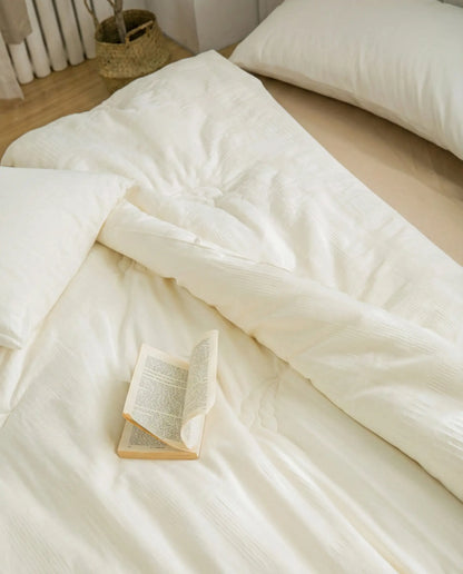 Organic soybean fiber duvet insert styled on neutral minimalist bed with open book, breathable hypoallergenic duvet insert with cotton shell.