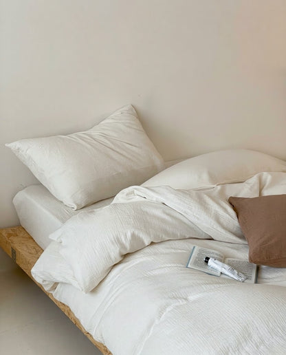 Relaxed Pearl muslin cotton double gauze duvet cover set on a wooden platform bed with a brown pillow
