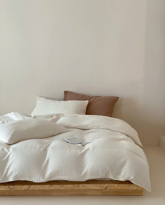 Pearl muslin cotton double gauze duvet cover set on a low wooden bed with a brown accent pillow