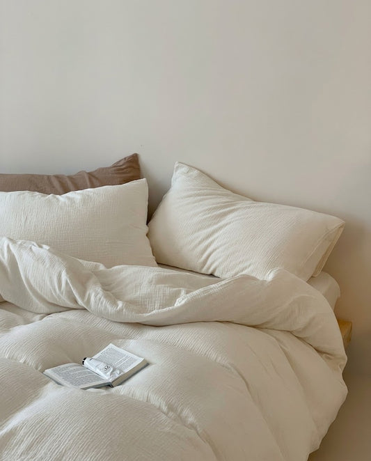 Pearl muslin cotton double gauze pillowcases and softly rumpled duvet cover with an open book