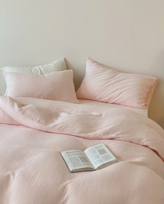 Petal muslin cotton double gauze duvet cover and pillowcases on a bed with a cream pillow and open book