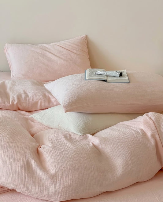 Petal muslin cotton double gauze pillowcases on a softly rumpled duvet cover with an open book