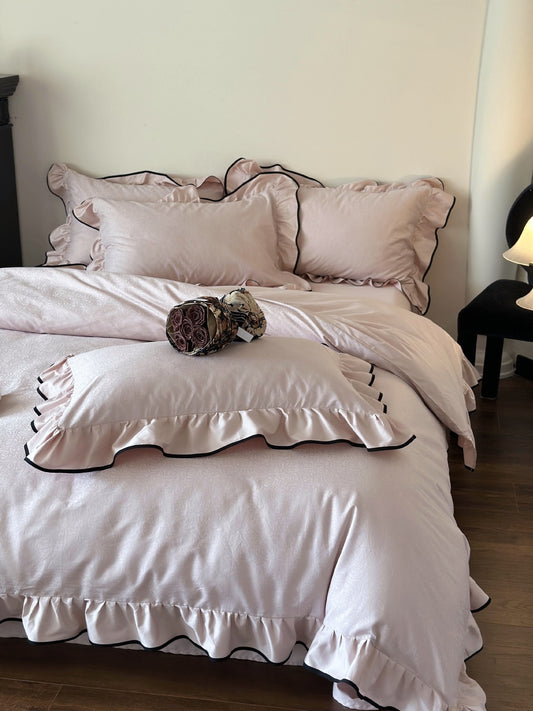Pale pink Camellia Ruffled Duvet Cover Set in Quartz with ruffled pillow shams and black piping