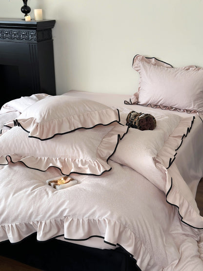 Camellia Ruffled Duvet Cover Set in Quartz with ruffled shams and black trim in a styled bedroom