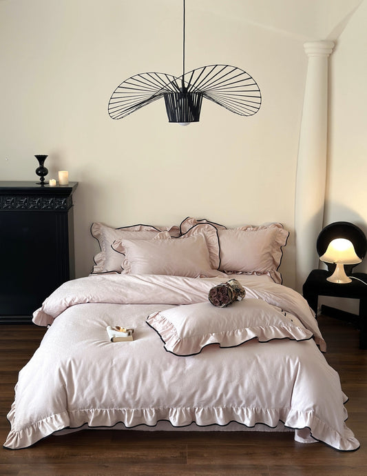 Quartz pink Camelia Ruffled Duvet Cover Set styled in a bedroom with black fireplace and pendant light