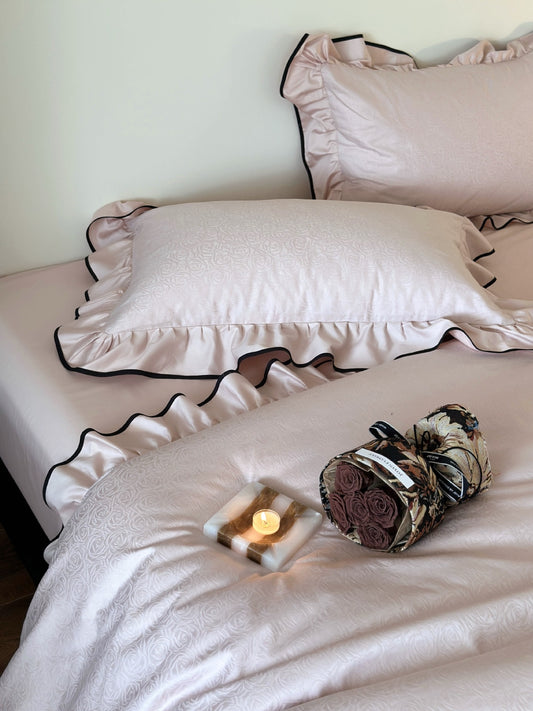 Camellia Ruffled Duvet Cover Set in Quartz with rose jacquard duvet cover, styled with a candle and bouquet