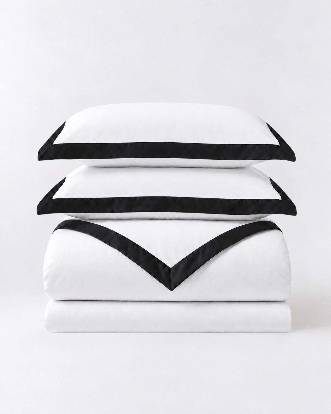 Folded white duvet cover set with black trim and matching pillowcases on neutral studio background