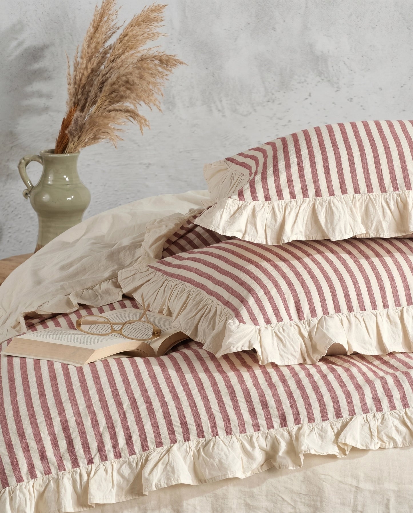 Close up of blush pink striped cotton pillow shams with soft ivory ruffle trim and elegant heirloom bedding texture