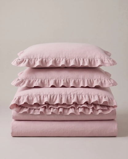 Folded blush pink ruffle bedding set featuring soft washed cotton fabric and romantic layered ruffle trim by DORMÉ Studio