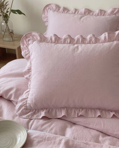 Close-up of blush pink ruffle pillow shams with soft textured cotton fabric and delicate romantic trim details by DORMÉ Studio