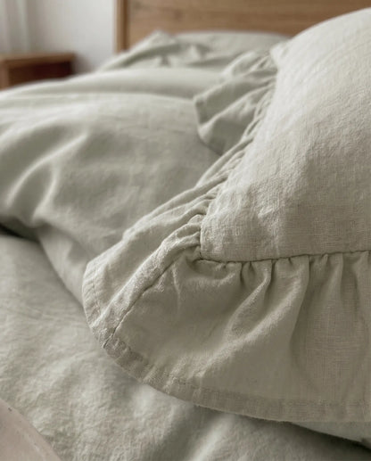 Close-up of the DORMÉ Studio Rosalie eucalyptus sage ruffle duvet cover set featuring soft textured cotton fabric and elegant gathered trim