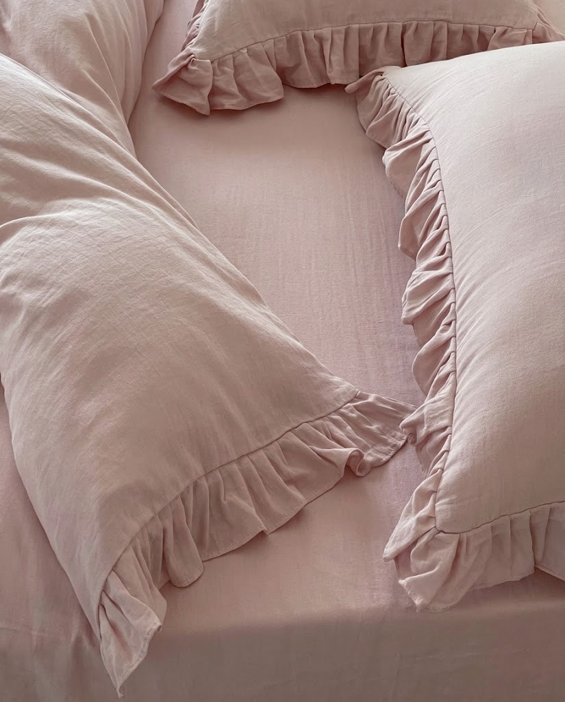 Overhead close-up of the Rosalie blush pink duvet cover and pillow sham showing gathered ruffle trim and soft cotton texture