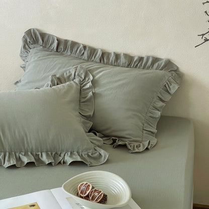 Eucalyptus sage ruffle pillow shams from the Rosalie duvet cover set in 100% cotton, styled with a ceramic bowl and open book