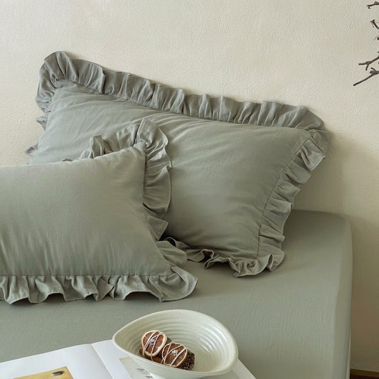 Eucalyptus sage ruffle pillow shams from the Rosalie duvet cover set in 100% cotton, styled with a ceramic bowl and open book