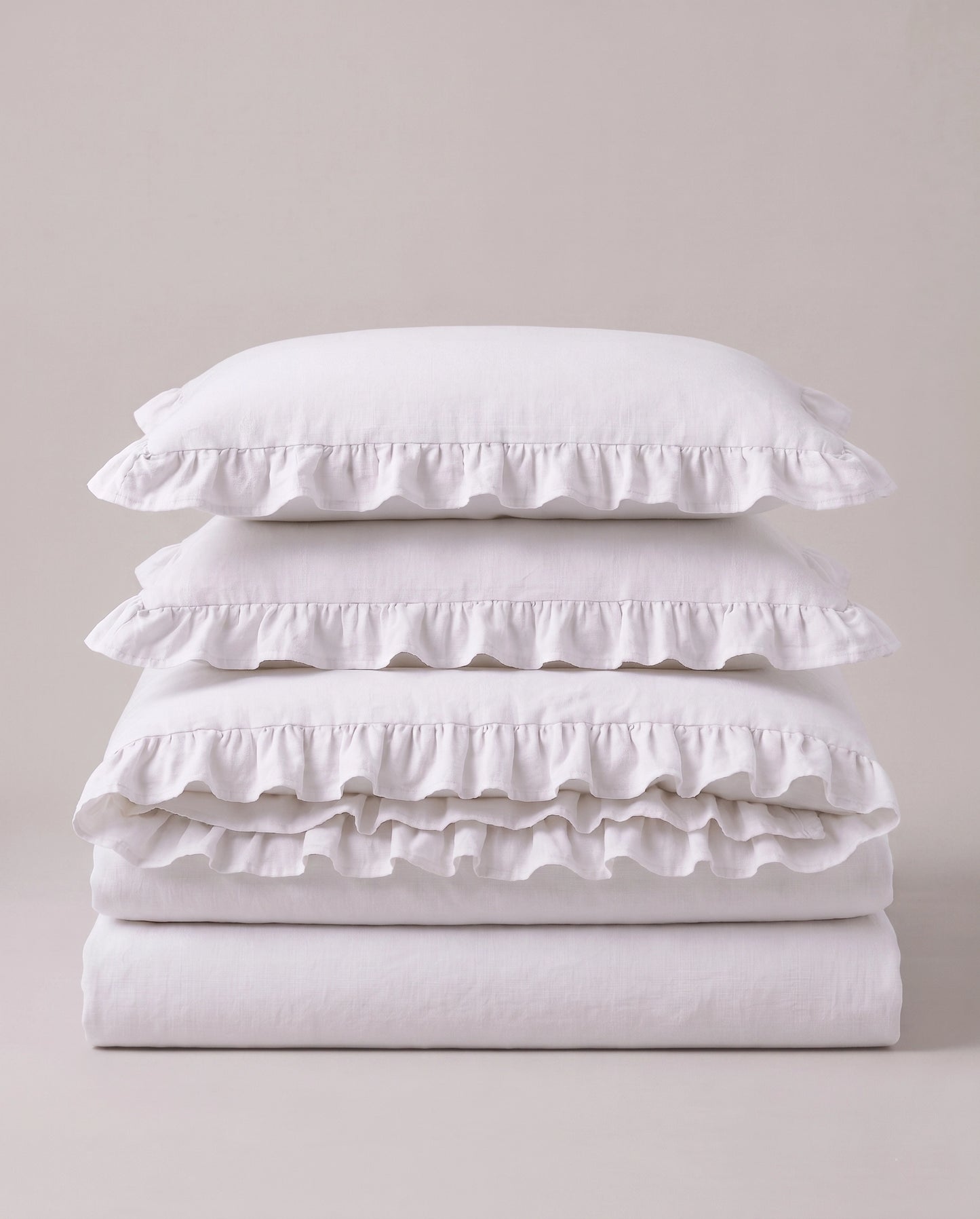 Folded snow white ruffle bedding set showcasing soft washed cotton fabric and elegant layered ruffle detailing by DORMÉ Studio