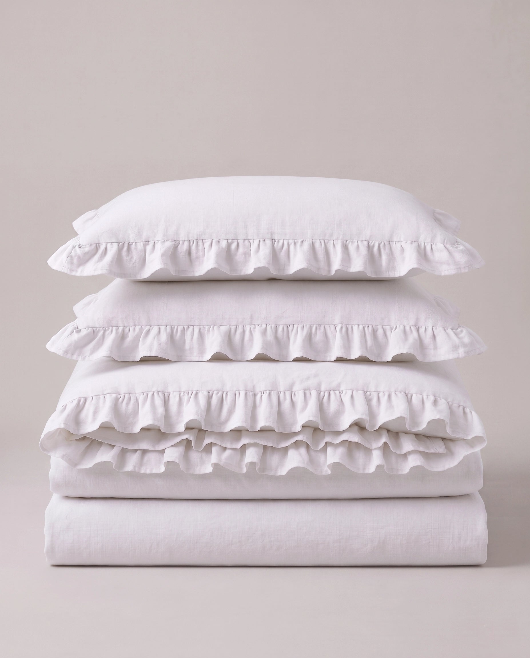Folded snow white ruffle bedding set showcasing soft washed cotton fabric and elegant layered ruffle detailing by DORMÉ Studio