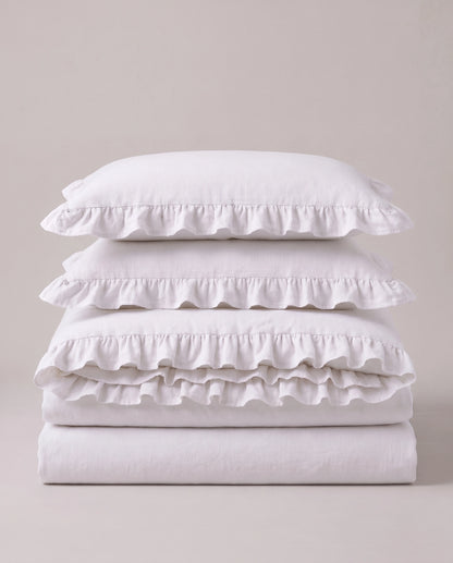 Folded snow white ruffle bedding set showcasing soft washed cotton fabric and elegant layered ruffle detailing by DORMÉ Studio