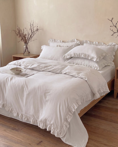 Snow white ruffle duvet cover set styled in a warm neutral bedroom featuring soft luxury bedding and elegant feminine details by DORMÉ Studio
