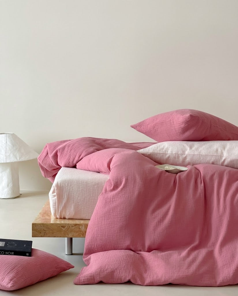 Rose muslin cotton double gauze duvet cover draped to the floor with a pillow and paper lamp