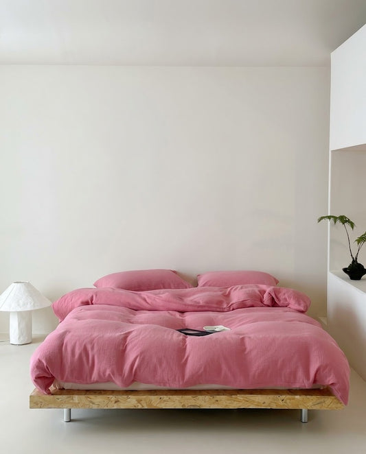 Rose muslin cotton double gauze duvet cover set on a low platform bed in a minimal bedroom with a paper lamp