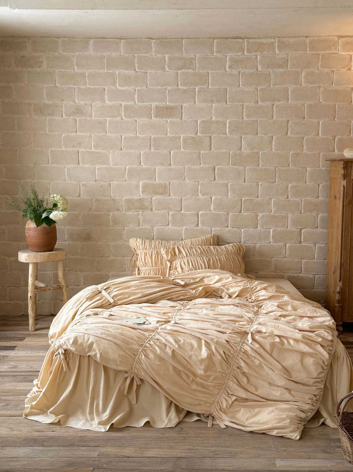 Front view of a cream ruched duvet cover set with bow ties, ruched pillowcases and ruffled bed skirt in washed cotton