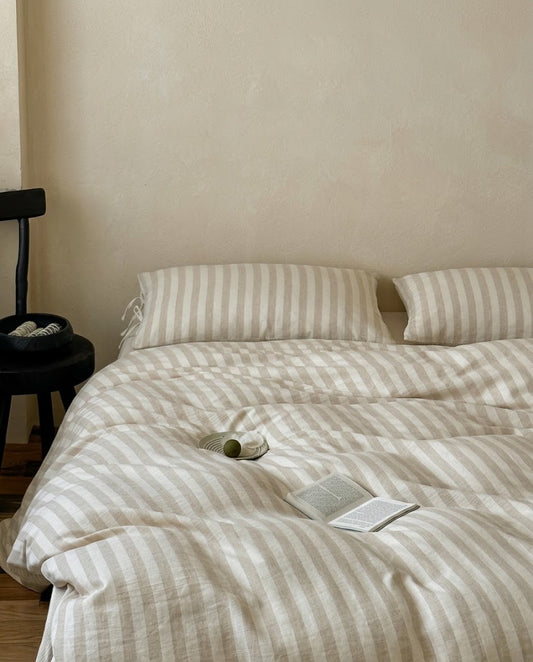 Sable Stripe Duvet Cover Set in cotton linen on a bed with two striped pillowcases against a warm neutral wall