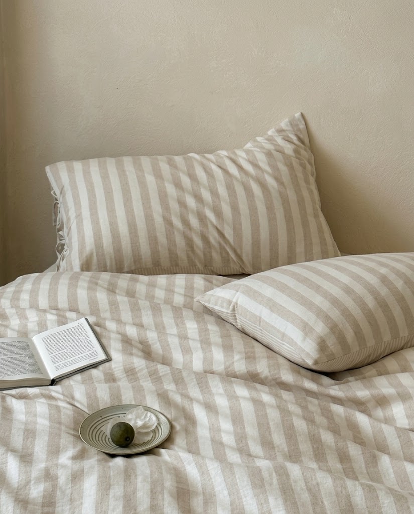 Close-up of oatmeal and cream striped pillowcases with side ties and pinstripe back on a matching duvet