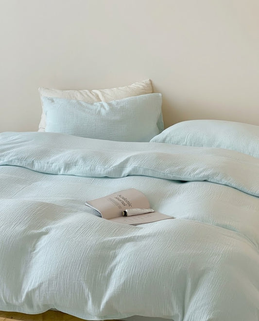Seafoam muslin cotton double gauze duvet cover and pillowcases with a cream pillow and open magazine