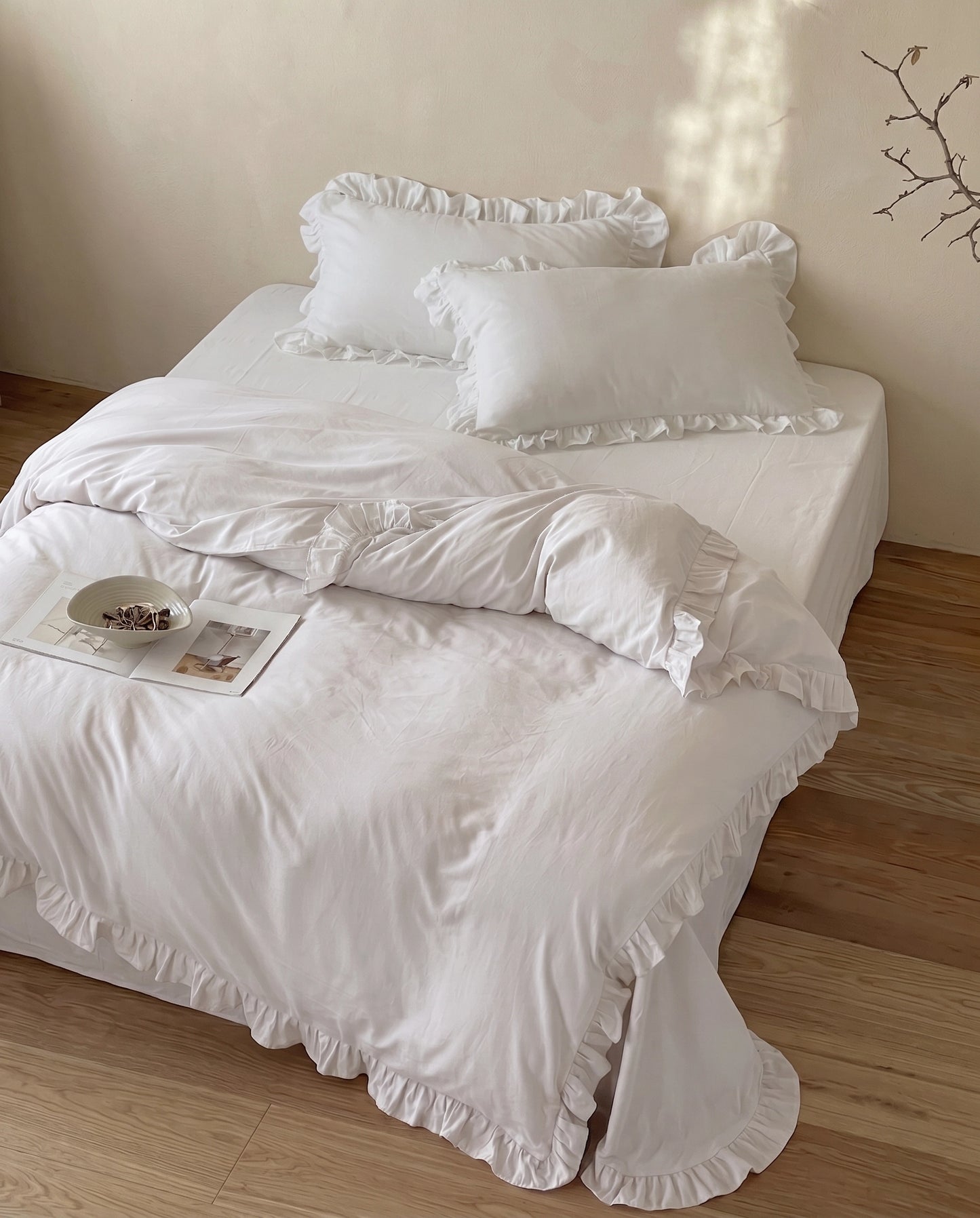 Luxury snow white ruffle duvet cover set with matching pillow shams styled on a minimalist bed by DORMÉ Studio