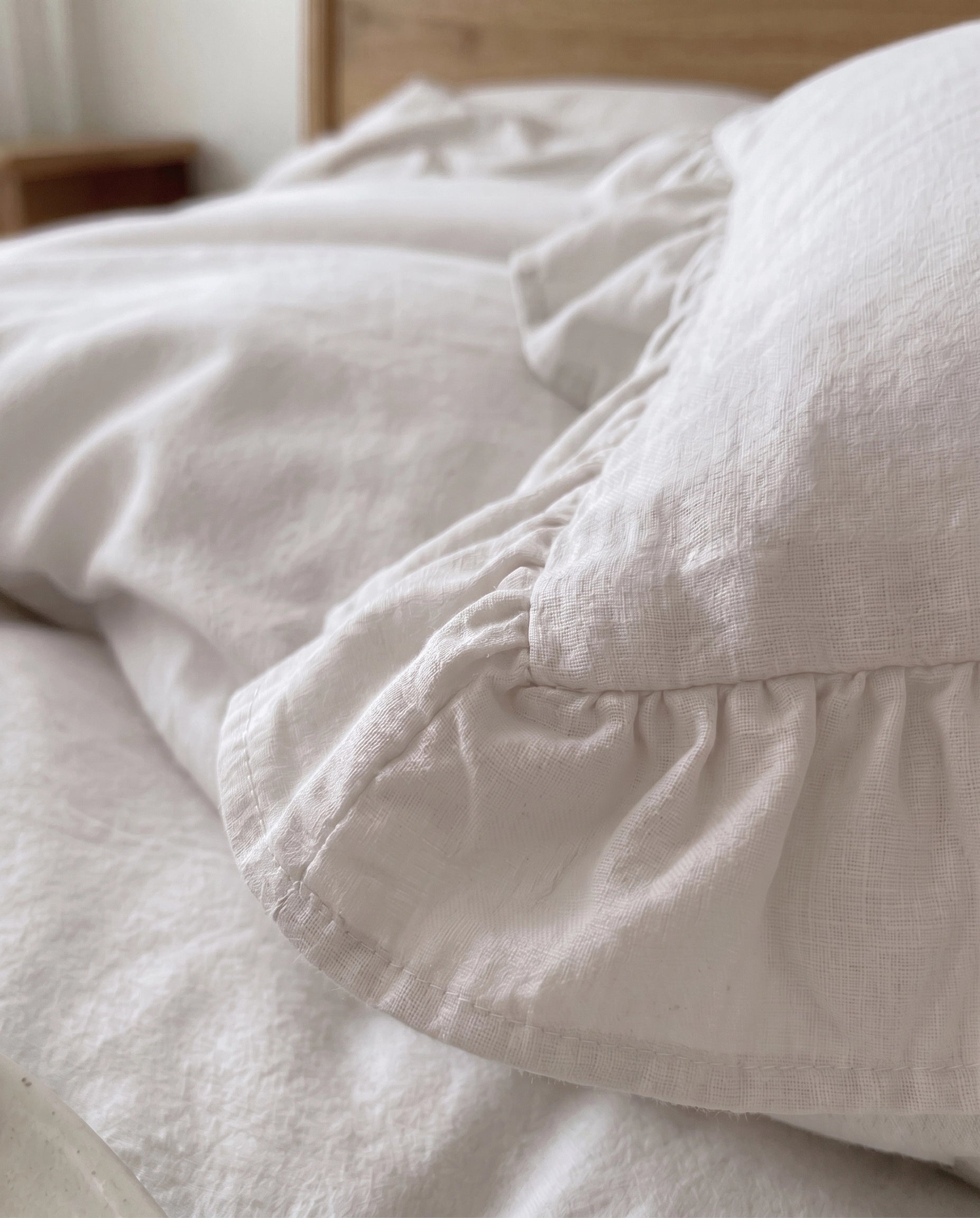 Close-up of snow white ruffle pillow sham featuring soft textured cotton fabric and delicate gathered trim by DORMÉ Studio