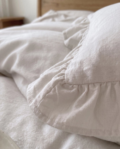 Close-up of snow white ruffle pillow sham featuring soft textured cotton fabric and delicate gathered trim by DORMÉ Studio
