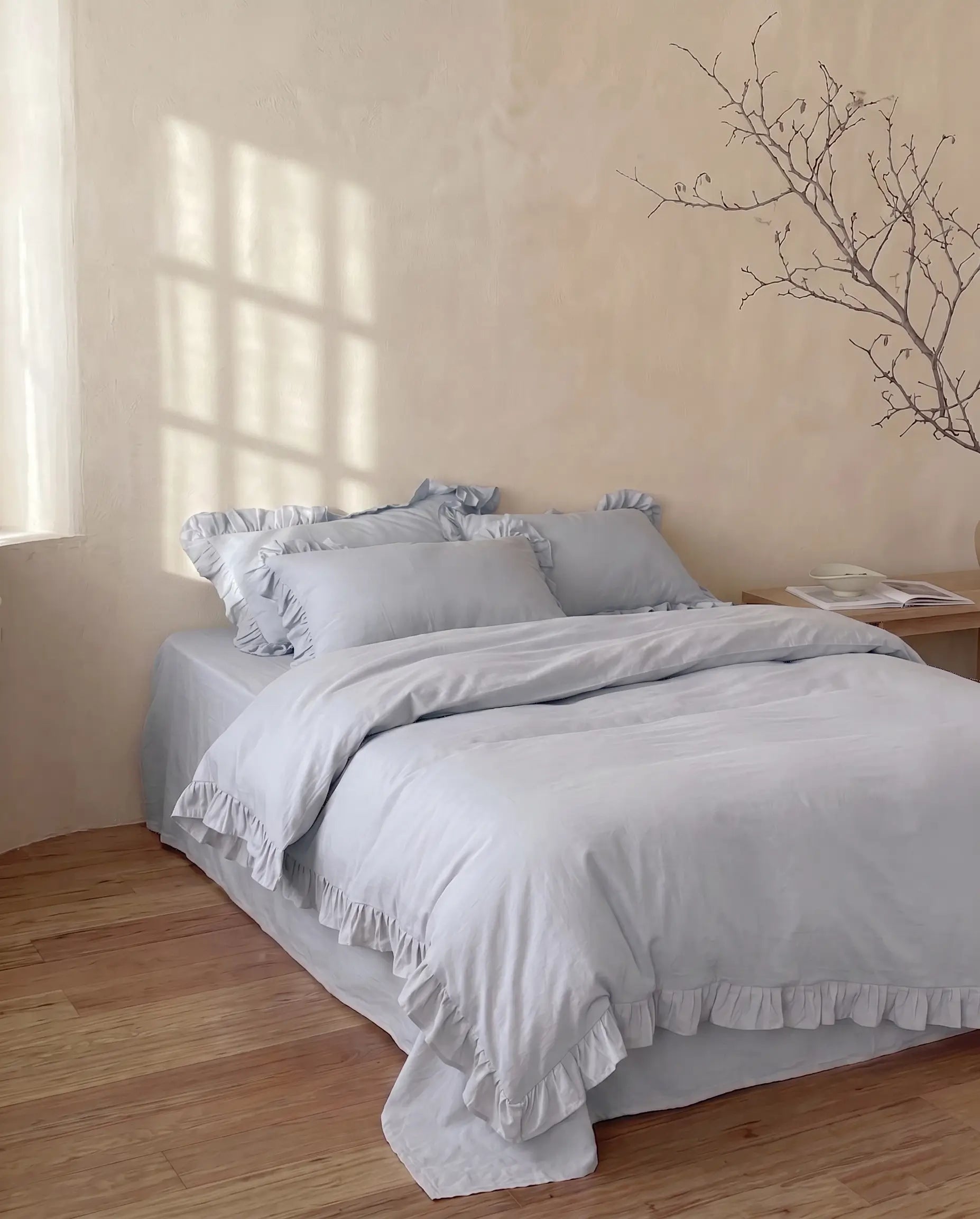 Soft mist blue duvet cover set with romantic ruffle edges styled in a calm minimalist bedroom