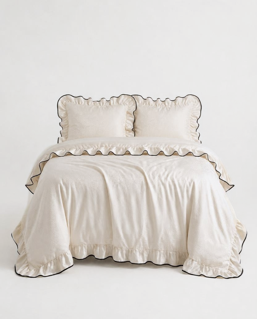Camellia Ruffled Duvet Cover Set in Ivory on a queen bed with ruffled pillow shams and black piped edges