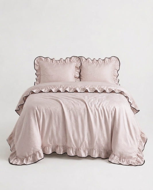 Camellia Ruffled Duvet Cover Set in Quartz on a bed with ruffled pillow shams and black piped edges