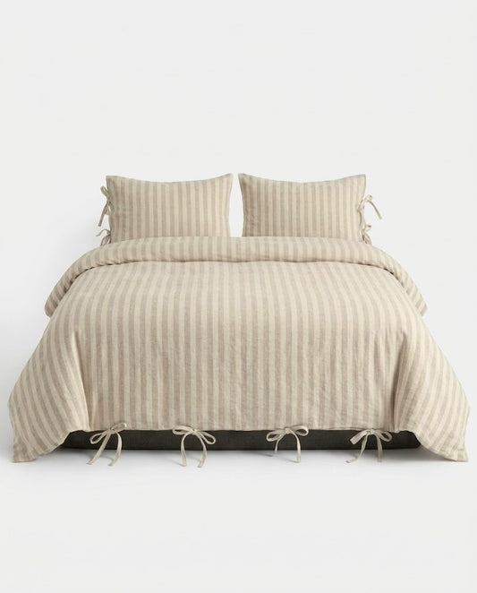 Sable Stripe Duvet Cover Set in oatmeal and cream on a made bed with bow tie closures and matching striped pillowcases