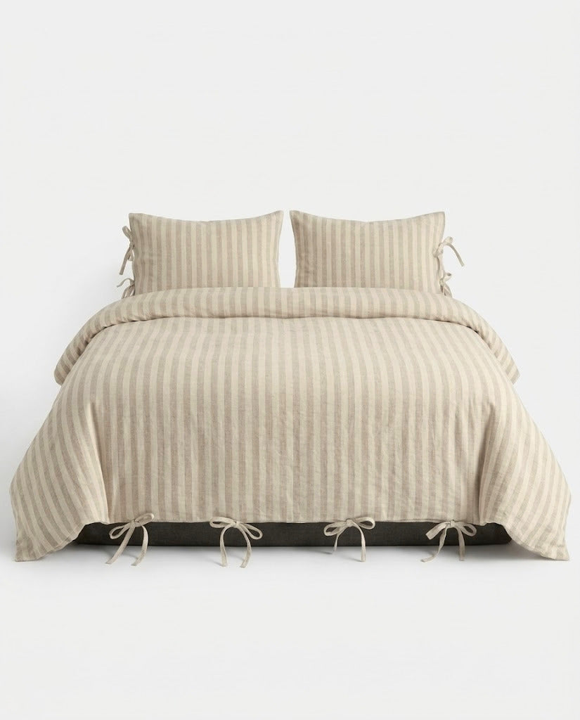 Sable Stripe Duvet Cover Set in oatmeal and cream on a made bed with bow tie closures and matching striped pillowcases