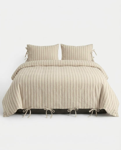 Sable Stripe Duvet Cover Set in oatmeal and cream on a made bed with bow tie closures and matching striped pillowcases