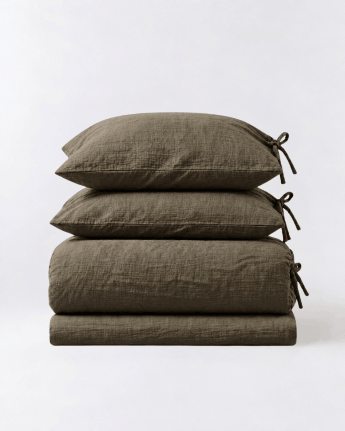 Folded Truffle muslin cotton duvet cover set by DORMÉ Studio showing duvet cover, flat sheet, and two tie-closure pillowcases