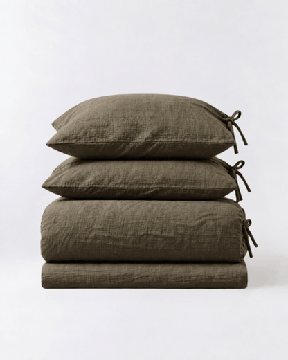 Folded Truffle muslin cotton duvet cover set by DORMÉ Studio showing duvet cover, flat sheet, and two tie-closure pillowcases