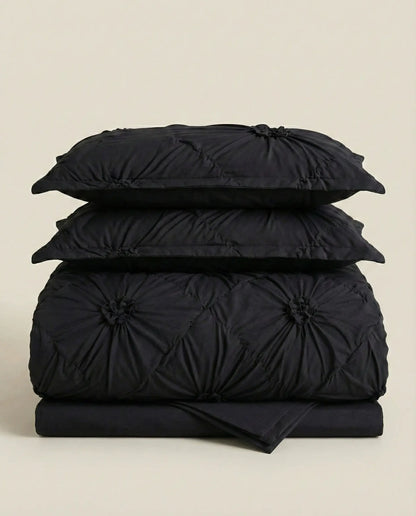 Folded black tufted duvet cover set stacked in studio lighting to showcase fabric texture and volume